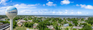 La Porte Water Tower Terry Thorn - Texas Hotel and Lodging Aerial view of La Porte, Texas: a tall blue-and-white water tower looms over a green, tree-filled residential neighborhood with Galveston Bay on the horizon.