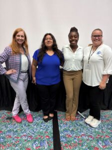 CTAT Panel - Teachers and Students - Texas Hotel and Lodging Four women stand side by side, smiling for a group photo indoors, dressed in business casual outfits.