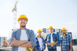 group of smiling builders in hardhats outdoors - Texas Hotel and Lodging